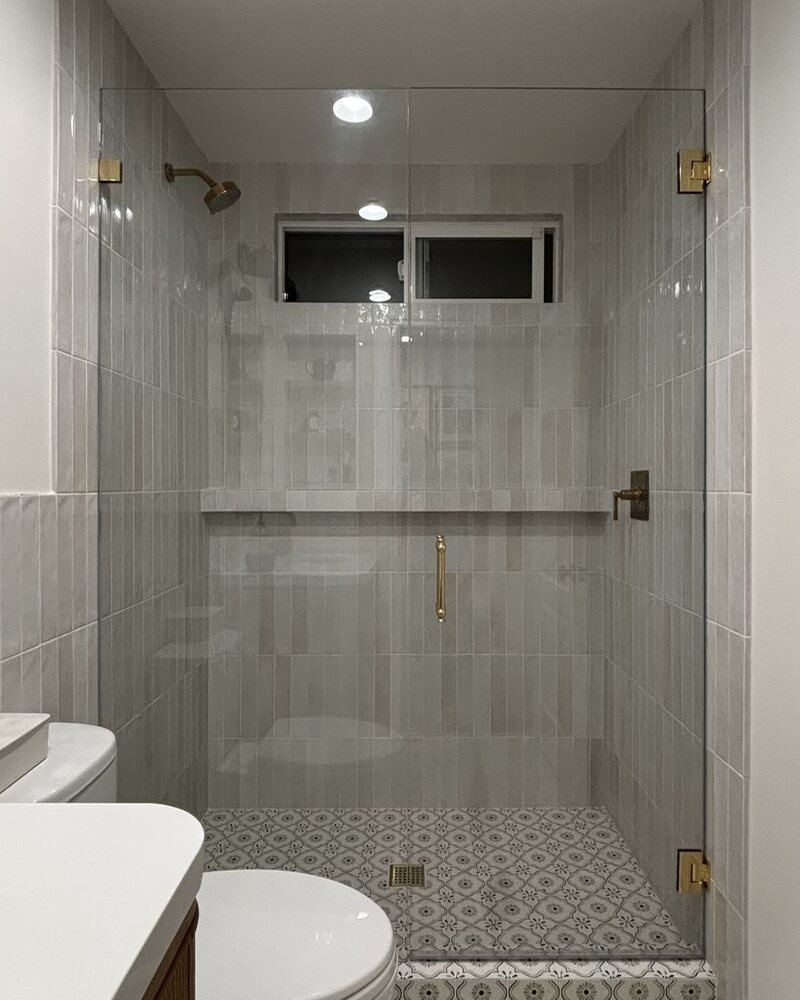 Frameless shower door with unlacquered brass hardware in Encinitas, CA